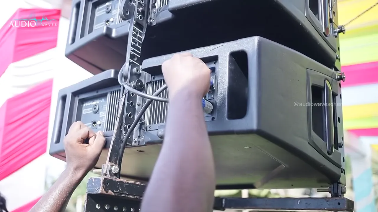 Crew fitting a line-array speaker onto its rigging at the beach party